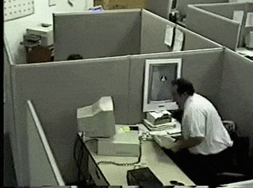 Man breaking computer at his desk at the worst job ever